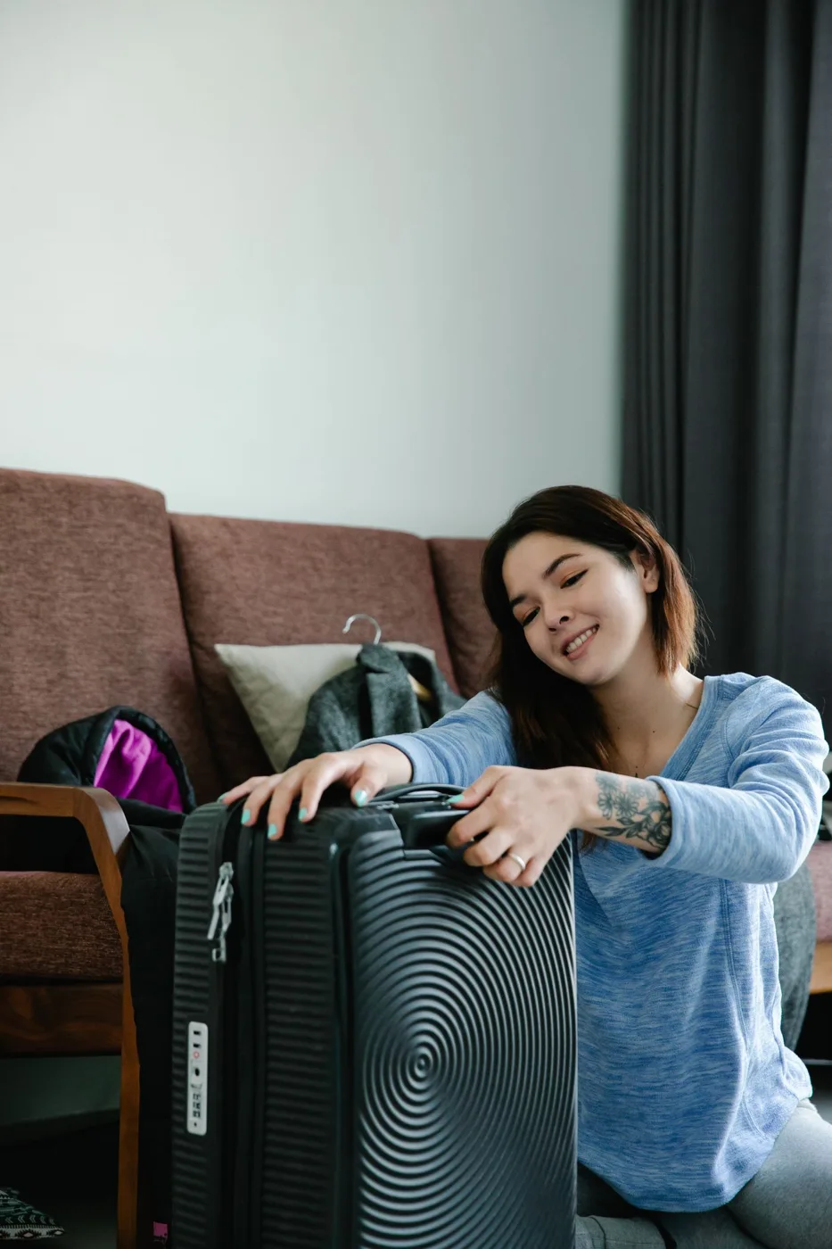 A woman with luggage beside a sofa at home