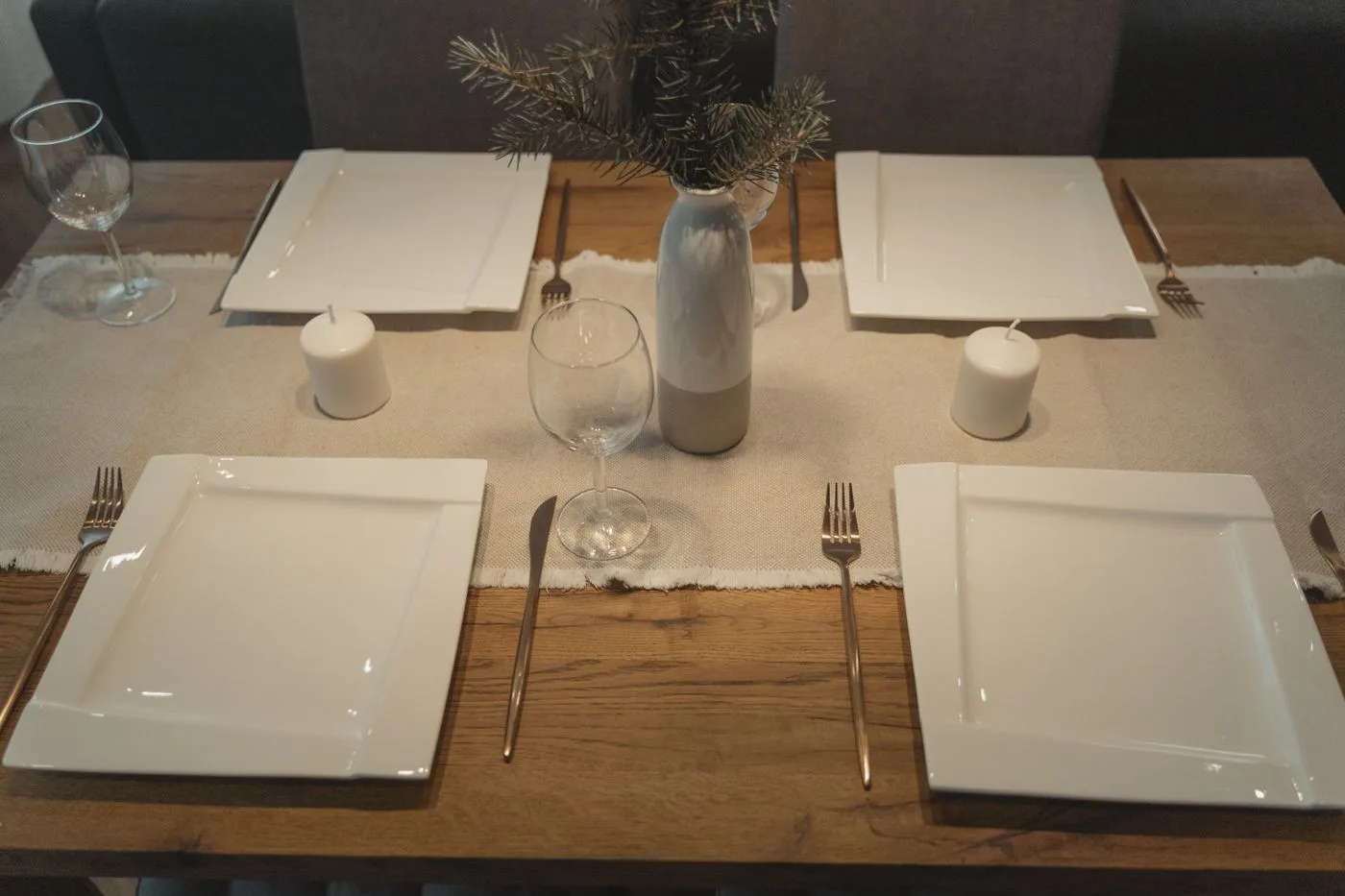 A dining table set with plates, glasses, and candles